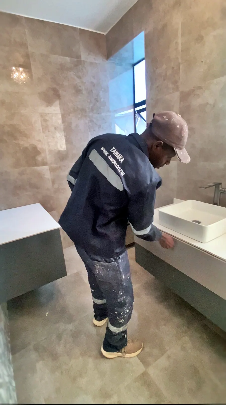 Tawaka Contracting fitting a countertop basin in a completed Greendale bathroom finished in large-format stone-effect