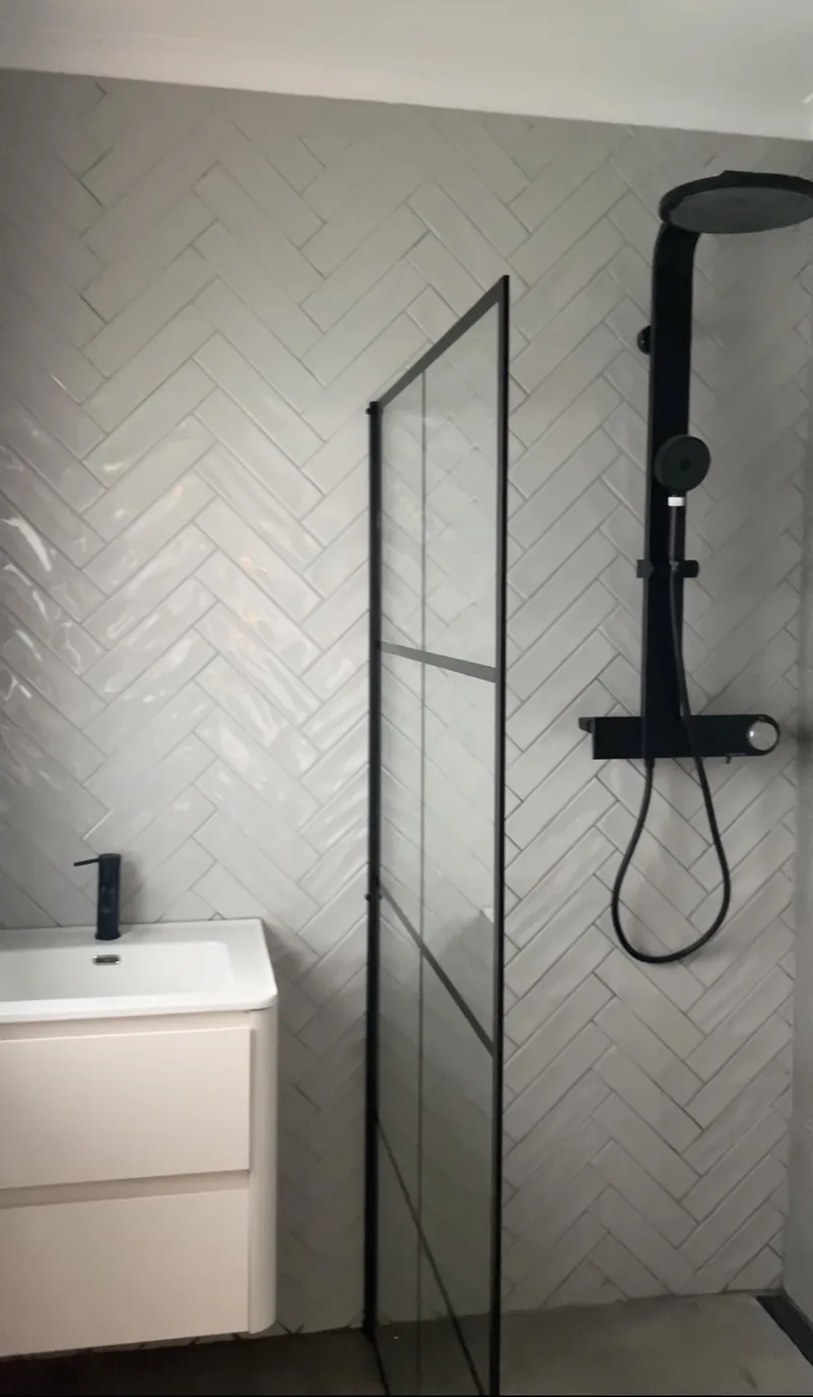Completed bathroom renovation by Tawaka Contracting in Harare, with white herringbone wall tiling, a black shower column and