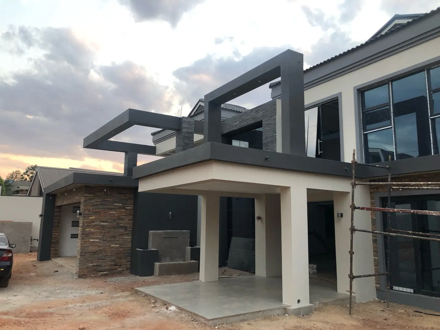 Residential painting contractor Harare — modern two-storey home with stone cladding and dark grey trim finished at dusk