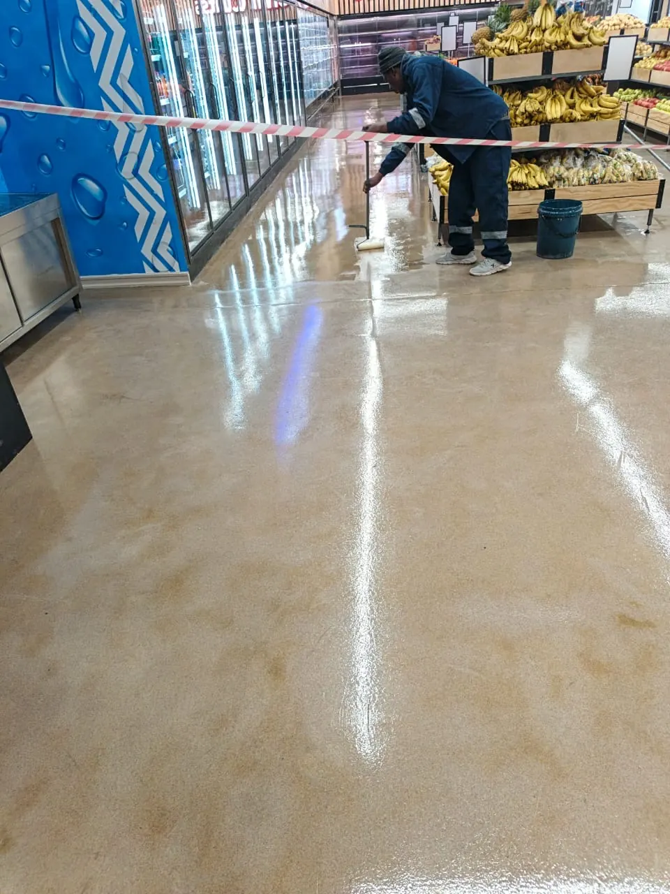 Tawaka Contracting operative applying a seamless resin floor coating inside a trading supermarket in Avondale, Harare
