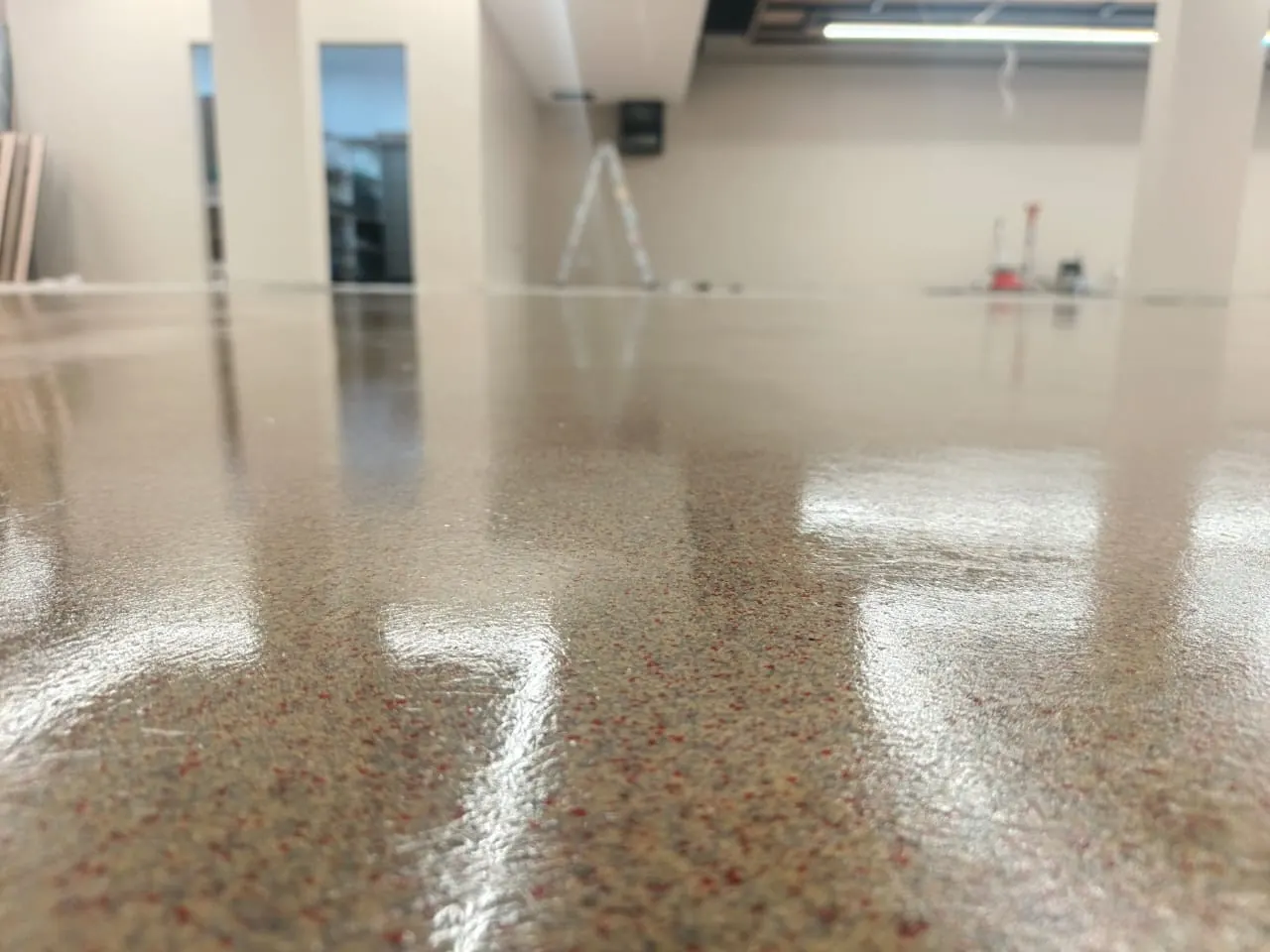 Close view of a cured seamless resin floor reflecting ceiling lights in a commercial interior, Zimbabwe