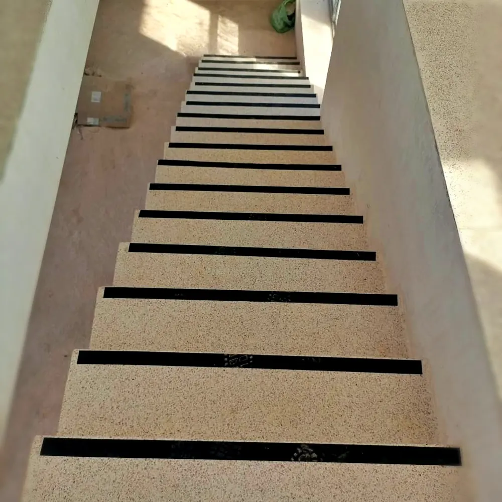 Terrazzo stairs Harare — long sand-toned terrazzo staircase between rendered walls with black anti-slip inlays