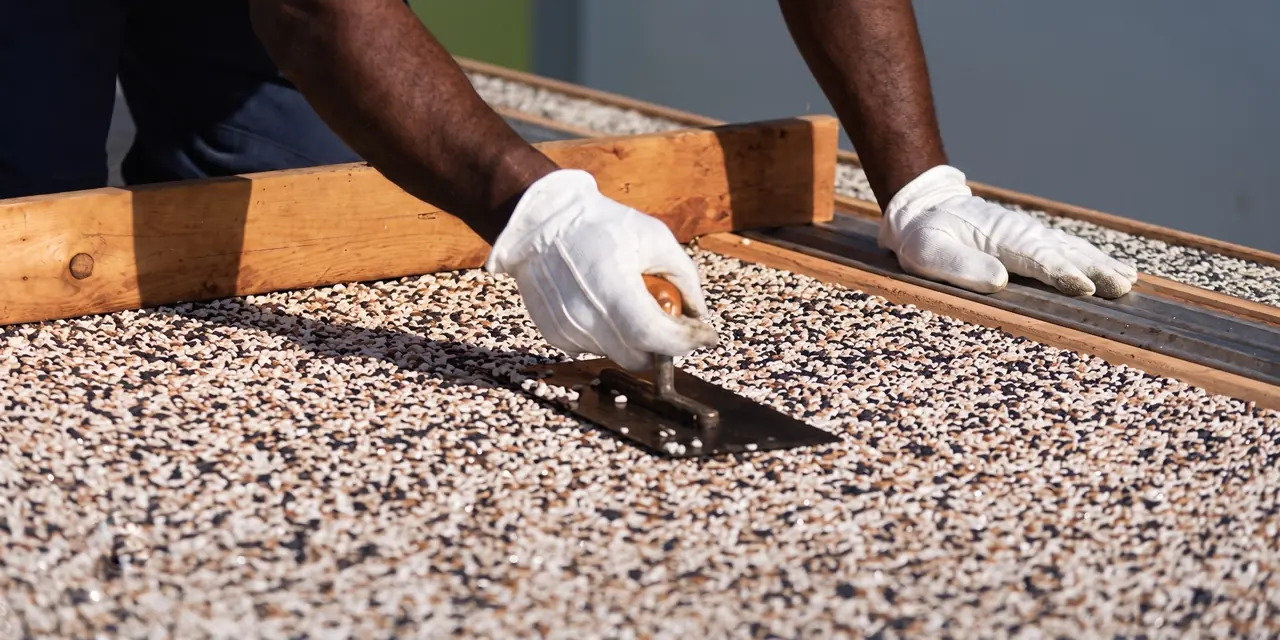 Terrazzo flooring Harare — craftsman hand-trowelling an exterior terrazzo aggregate screed to level